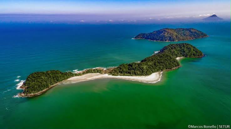 Vista aérea de ilha com faixa de areia e mar esmeralda